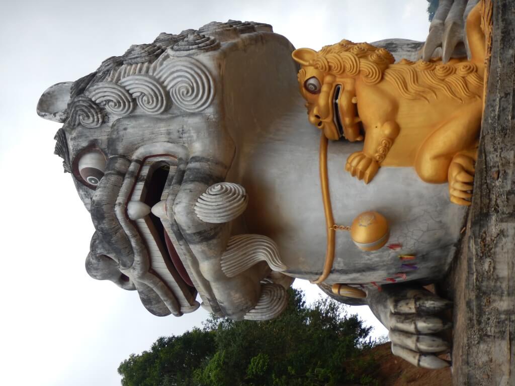 Mae Salong in Northern Thailand a huge grey statue of a Chinese lion and a golden baby lion hugging it