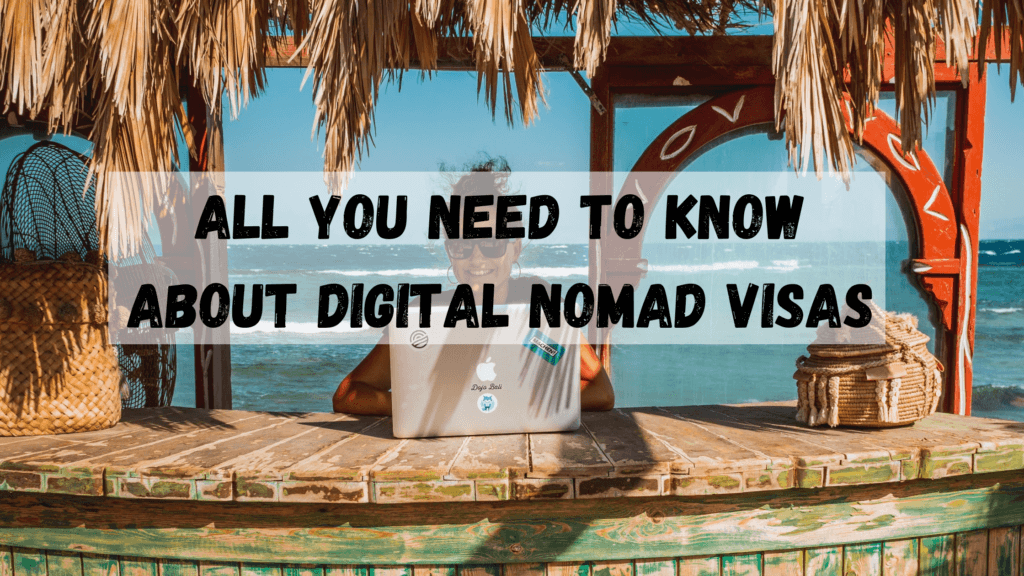 All you need to know about a digital nomad visa picture of a woman sitting at a wooden bar painted green with palm fronds over her head and the ocean in the background. 